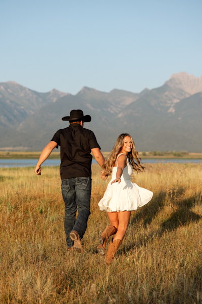 Rilee looking back at the camera while her and Colby run towards the Mission Mountains during their engagement session