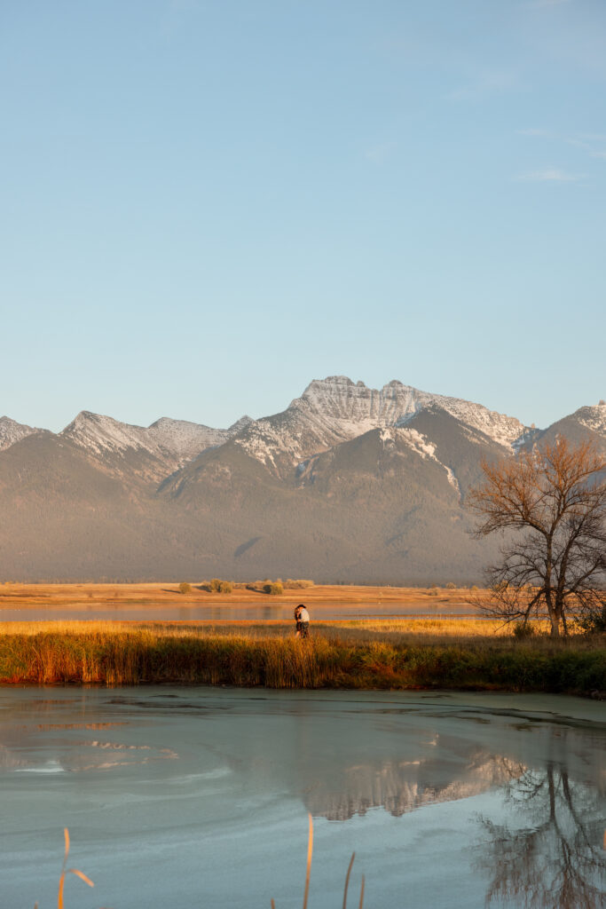 couple standing next to a pond in charlo montana during a mission mountain engagement session