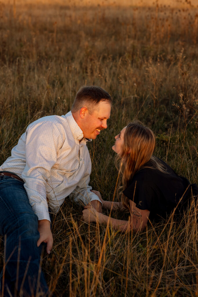 couple laying on the ground smiling during engagement session near st ignatius montana