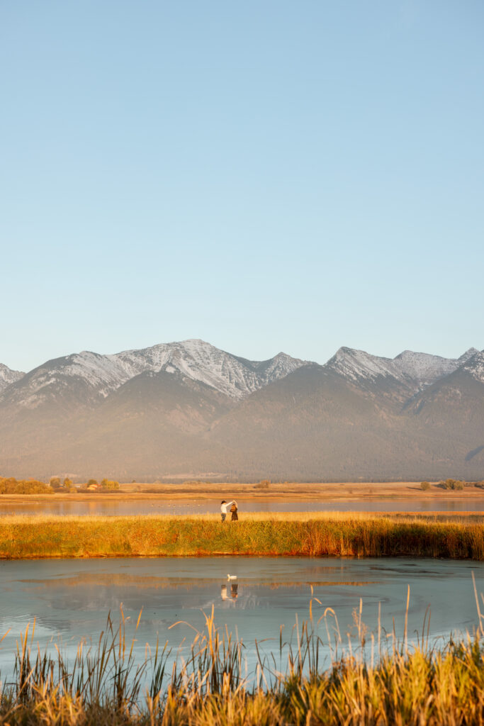 couple dancing across a pond with mission mountains in the back