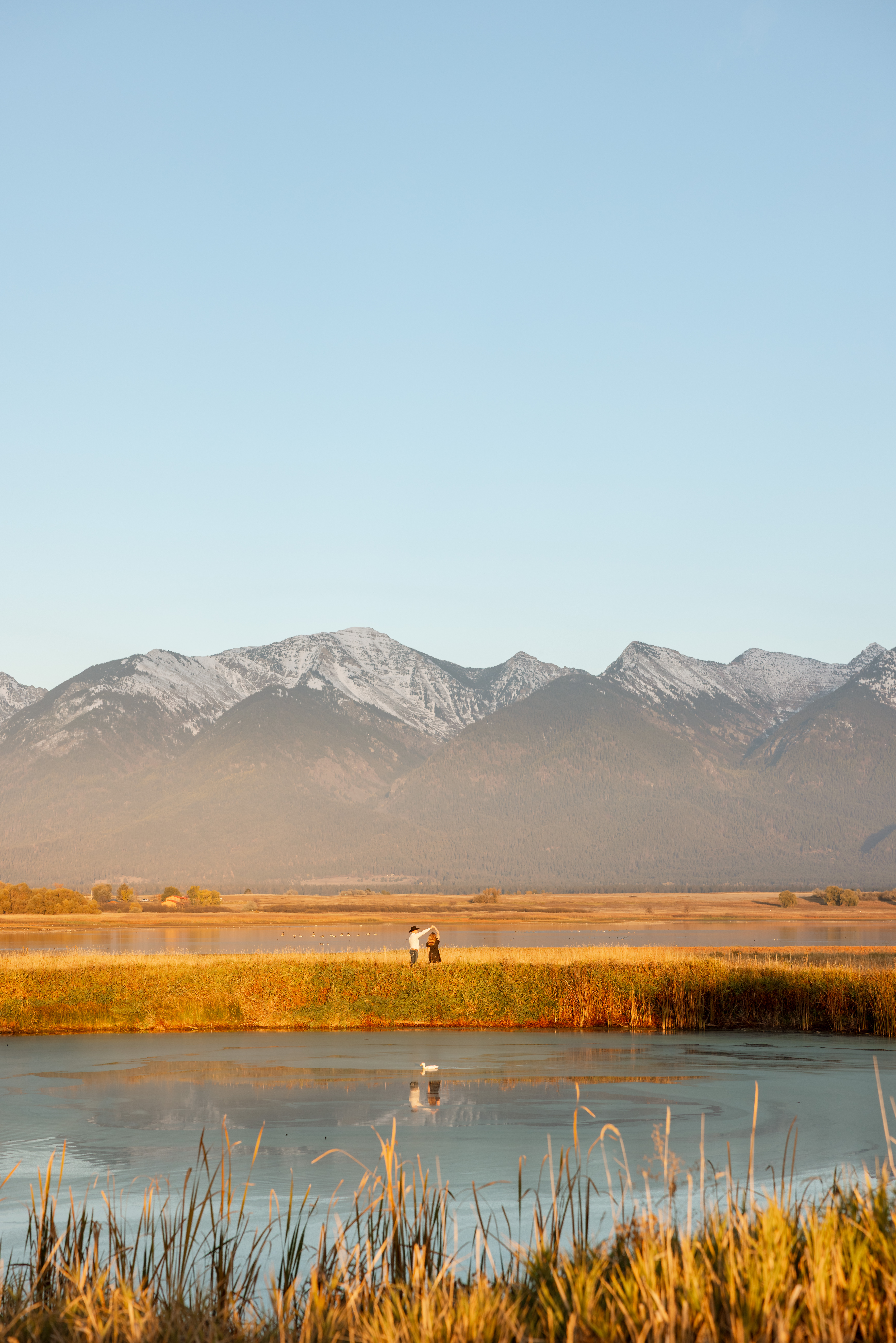 couple dancing in the distance with the mission mountains in the background