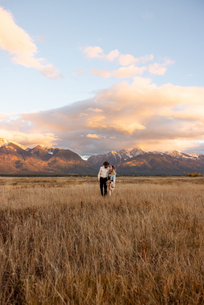 couple cuddled up and walking away from the mission mountains at sunset