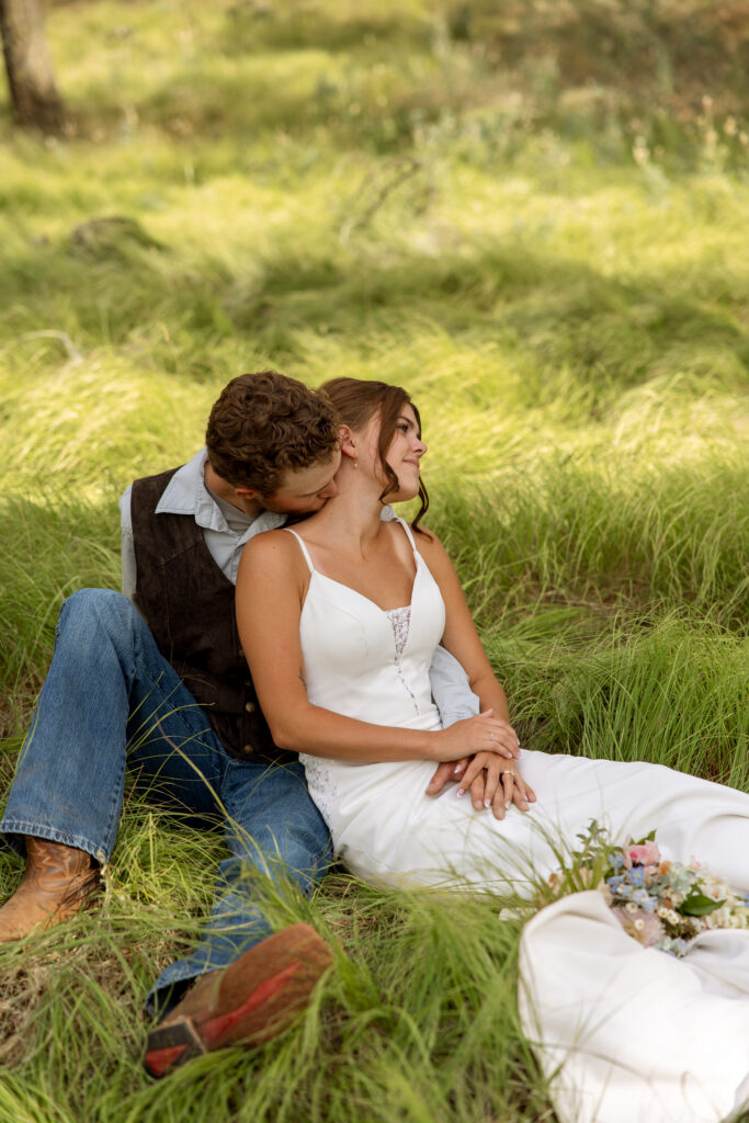 bride and groom snuggled up sitting in the grass