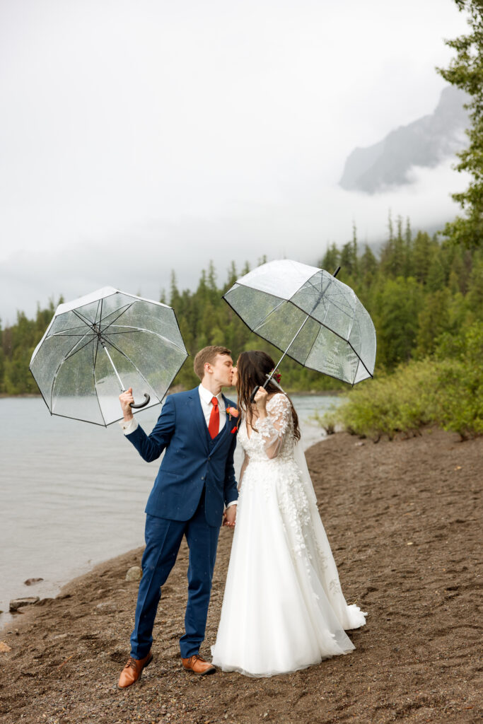 bride and groom kissing in the rain during glacier national park elopement