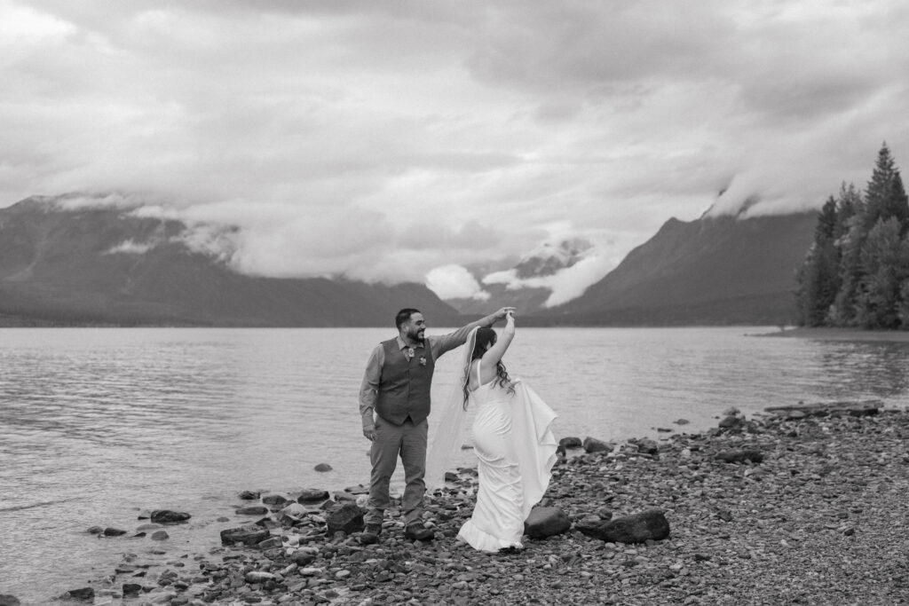 groom twirling bride next to lake mcdonald in glacier national park