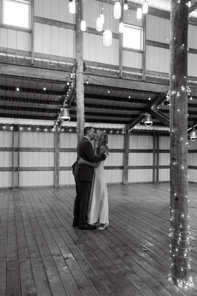 Black and white of bride and groom kissing surrounded by twinkle lights inside Diamond B Weddings — Kalispell Montana wedding photographer — Stacy Edwards Photography