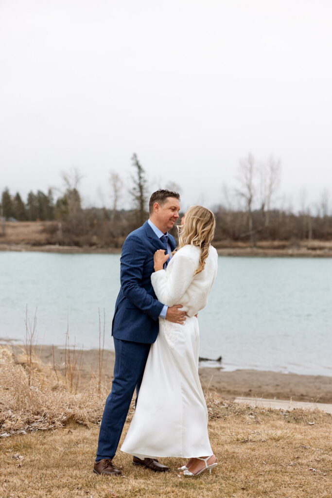Bride and groom standing face to face holding each other by the river, groom smiling at bride at Diamond B Weddings — Kalispell Montana wedding photographer — Stacy Edwards Photography