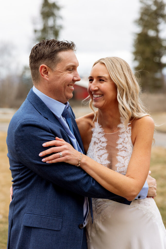 Bride and groom loosely hugging softly laughing and smiling at each other at Diamond B Weddings — Kalispell Montana wedding photographer — Stacy Edwards Photography
