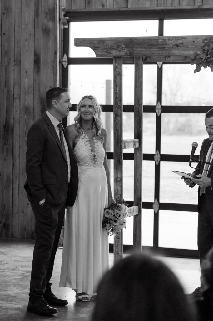 Black and white of bride smiling at groom at the altar during ceremony at Diamond B Weddings — Kalispell Montana wedding photographer — Stacy Edwards Photography