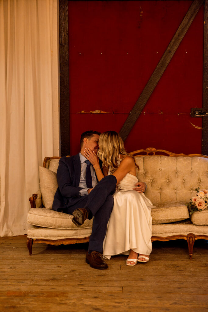 Bride and groom snuggling and smiling on decorative couch almost kissing at Diamond B Weddings — Kalispell Montana wedding photographer — Stacy Edwards Photography