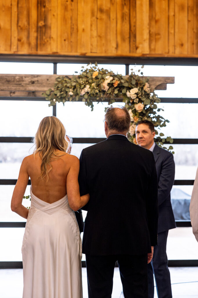 Bride and father walking toward groom at the altar shot from behind at Diamond B Weddings — Kalispell Montana wedding photographer — Stacy Edwards Photography