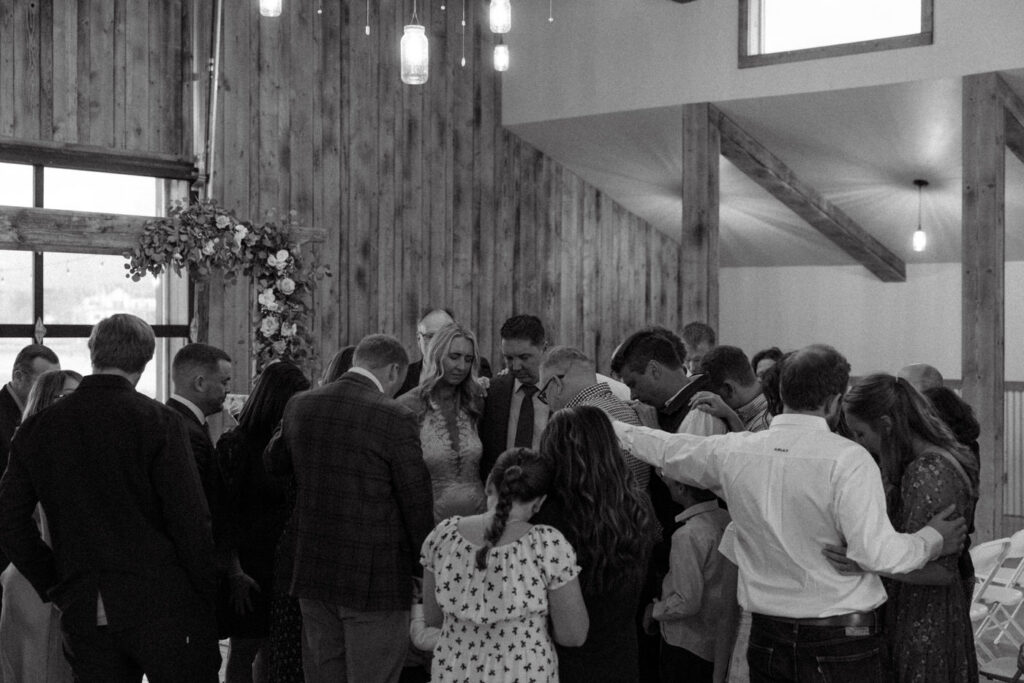 Candid of wedding guests praying over bride and groom during ceremony — Scott and Molly — Diamond B Weddings Kalispell Montana — Stacy Edwards Photography