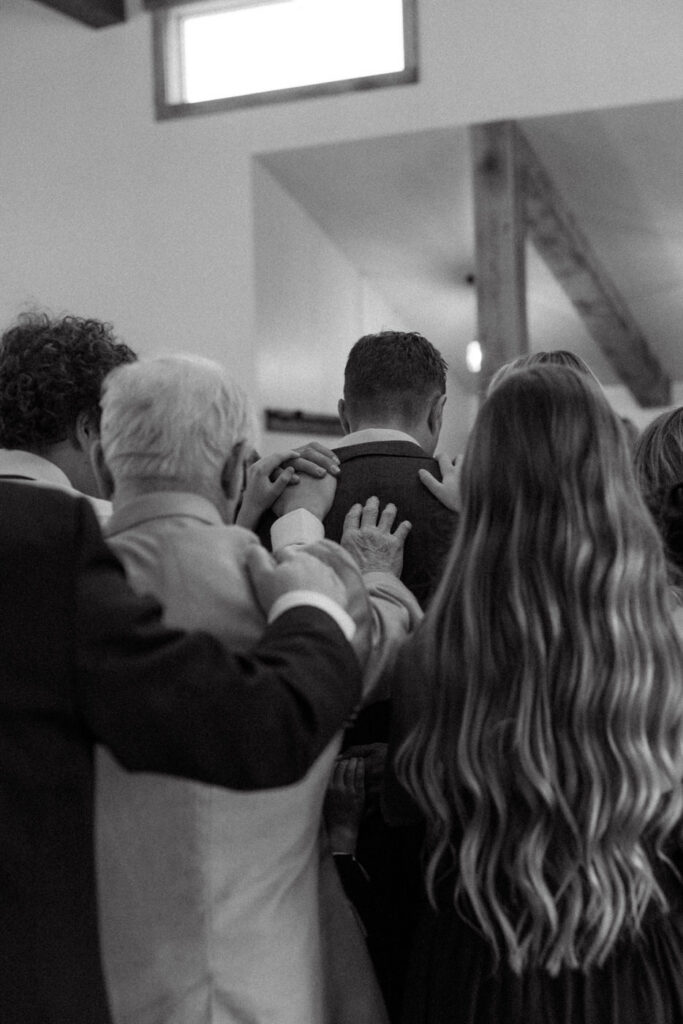 Guests laying hands on bride and groom during prayer circle ceremony moment — Scott and Molly — Diamond B Weddings Kalispell Montana — Stacy Edwards Photography
