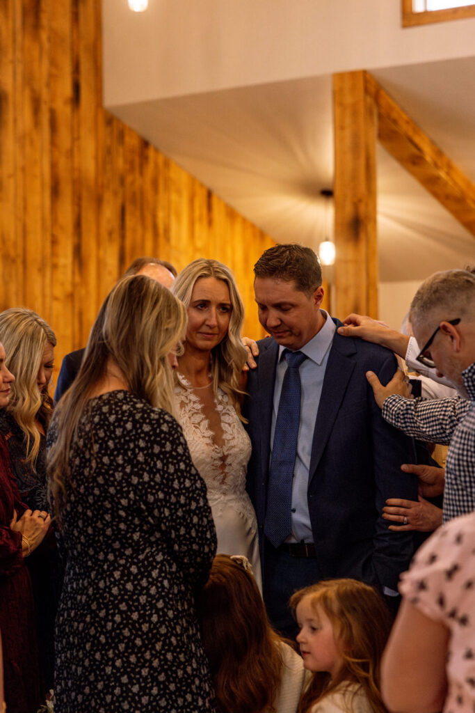 Intimate prayer circle moment with bride and groom centered among wedding guests — Scott and Molly — Diamond B Weddings Kalispell Montana — Stacy Edwards Photography