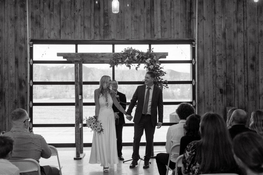 Black and white of bride and groom holding hands after first kiss — Scott and Molly — Diamond B Weddings Kalispell Montana — Stacy Edwards Photography