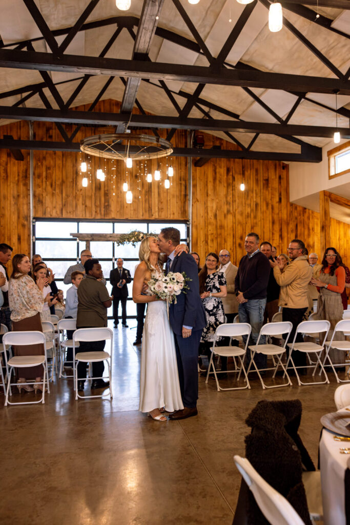 Bride and groom kissing at the end of the aisle after recessional — Scott and Molly — Diamond B Weddings Kalispell Montana — Stacy Edwards Photography