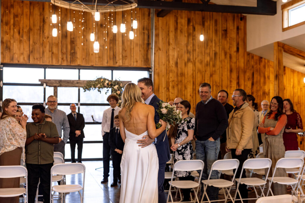 Groom smiling at bride after recessional with guests standing behind them — Scott and Molly — Diamond B Weddings Kalispell Montana — Stacy Edwards Photography