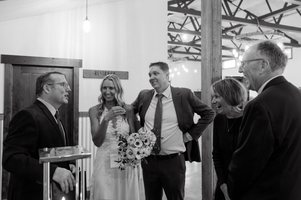 Black and white of bride and groom laughing with officiant and bride's parents after signing marriage license — Scott and Molly — Diamond B Weddings Kalispell Montana — Stacy Edwards Photography