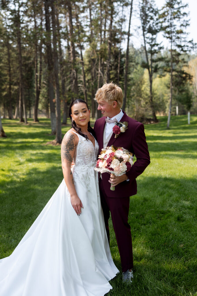 Bride and groom portrait on the Montana lawn, she leaning into his shoulder as he looks down at her with a soft smile, bouquet in hand — Mikayla + Cayden — Haymoon Resort Wedding — Whitefish Montana — Stacy Edwards Photography