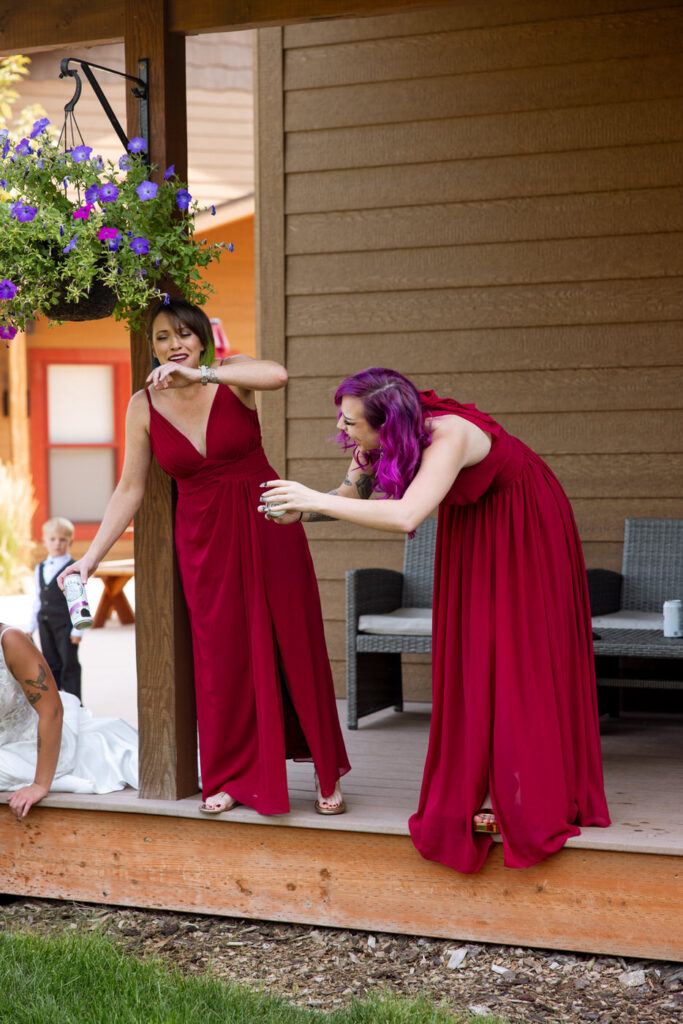 Candid of two bridesmaids in burgundy dresses laughing on the Haymoon Resort cabin porch — Mikayla + Cayden — Haymoon Resort Wedding — Whitefish Montana — Stacy Edwards Photography