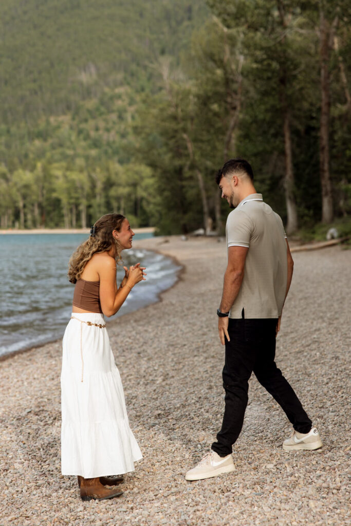Woman laughing with hands clasped in excitement after surprise proposal at Apgar Village, Lake McDonald — Ryan + Liz — Surprise Proposal — Glacier National Park — Stacy Edwards Photography
