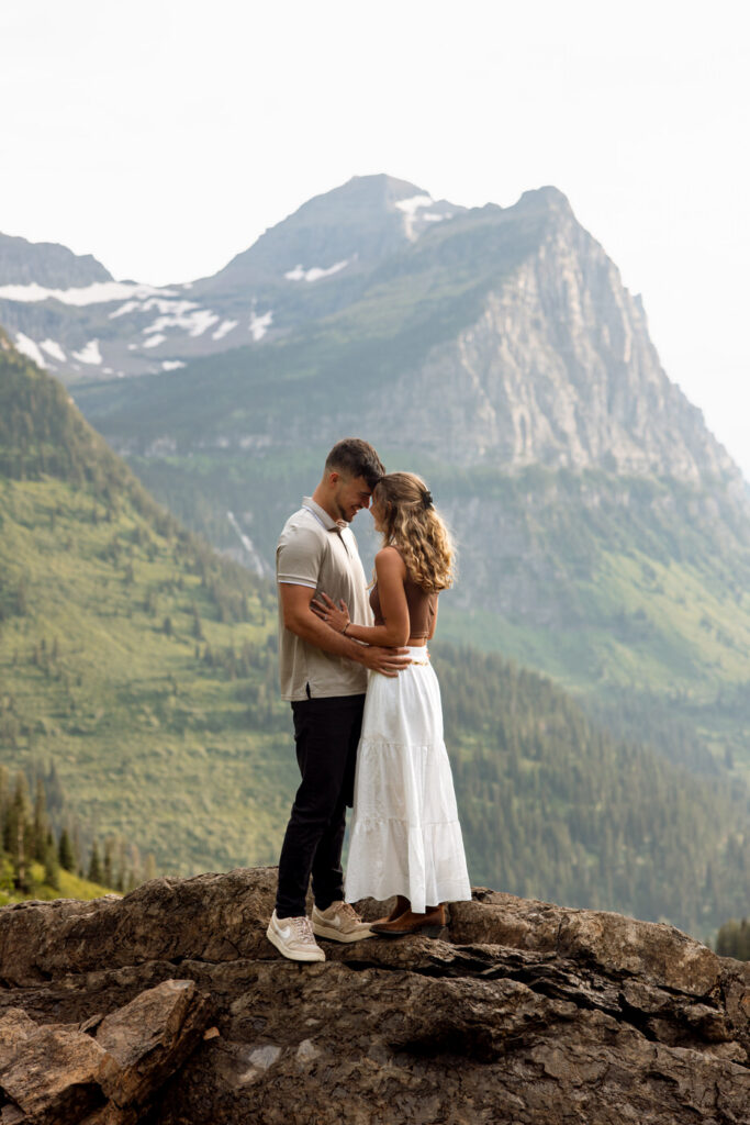 Engaged couple touching foreheads in a quiet, intimate moment on a rocky overlook along Going to the Sun Road — Ryan + Liz — Surprise Proposal — Glacier National Park — Stacy Edwards Photography