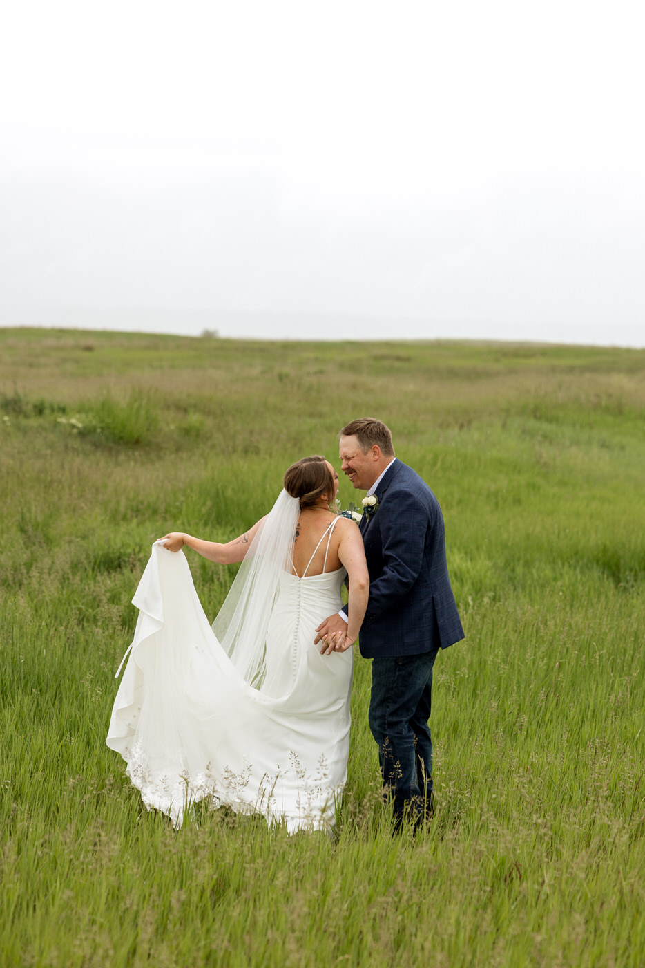 Photo from behind of bride and groom smiling at each other — Aislynn + Kyle — Mission Valley Wedding — Charlo Montana — Stacy Edwards Photography