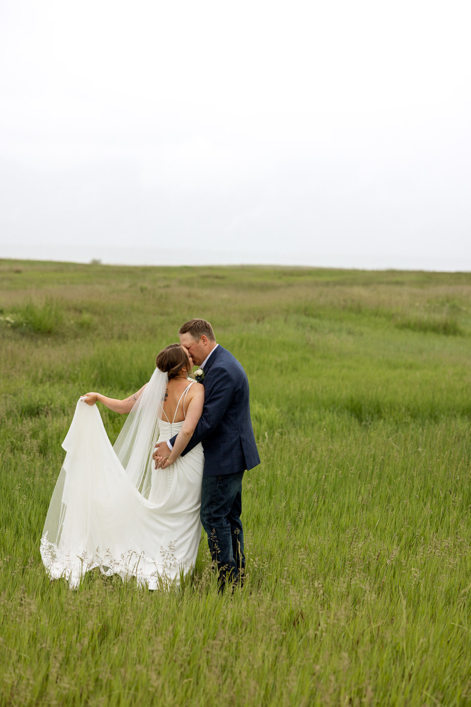Photo from behind of bride and groom kissing — Aislynn + Kyle — Mission Valley Wedding — Charlo Montana — Stacy Edwards Photography