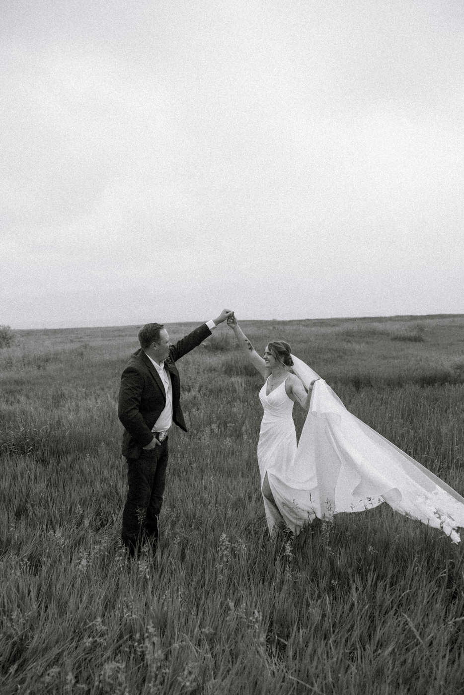Black and white photo of bride twirling around grooms finger — Aislynn + Kyle — Mission Valley Wedding — Charlo Montana — Stacy Edwards Photography