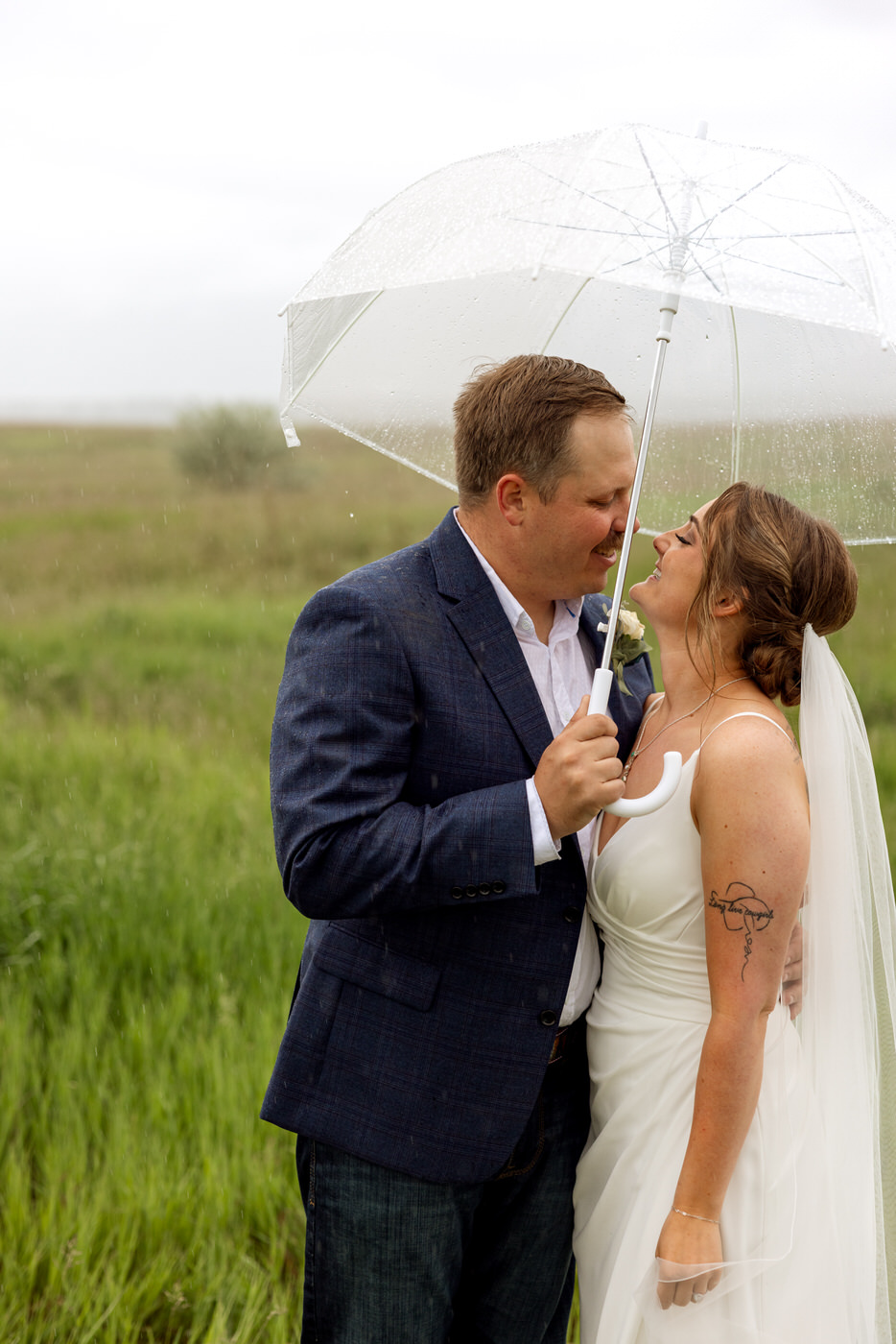 Bride and groom smiling at each other under an umbrella — Aislynn + Kyle — Mission Valley Wedding — Charlo Montana — Stacy Edwards Photography