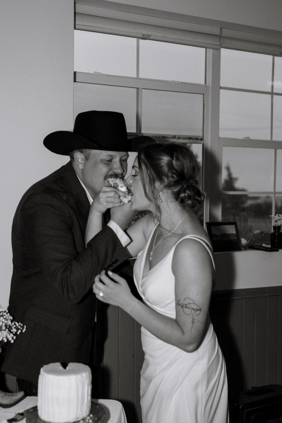 Black and white photo of bride and groom eating the wedding cake — Aislynn + Kyle — Mission Valley Wedding — Charlo Montana — Stacy Edwards Photography