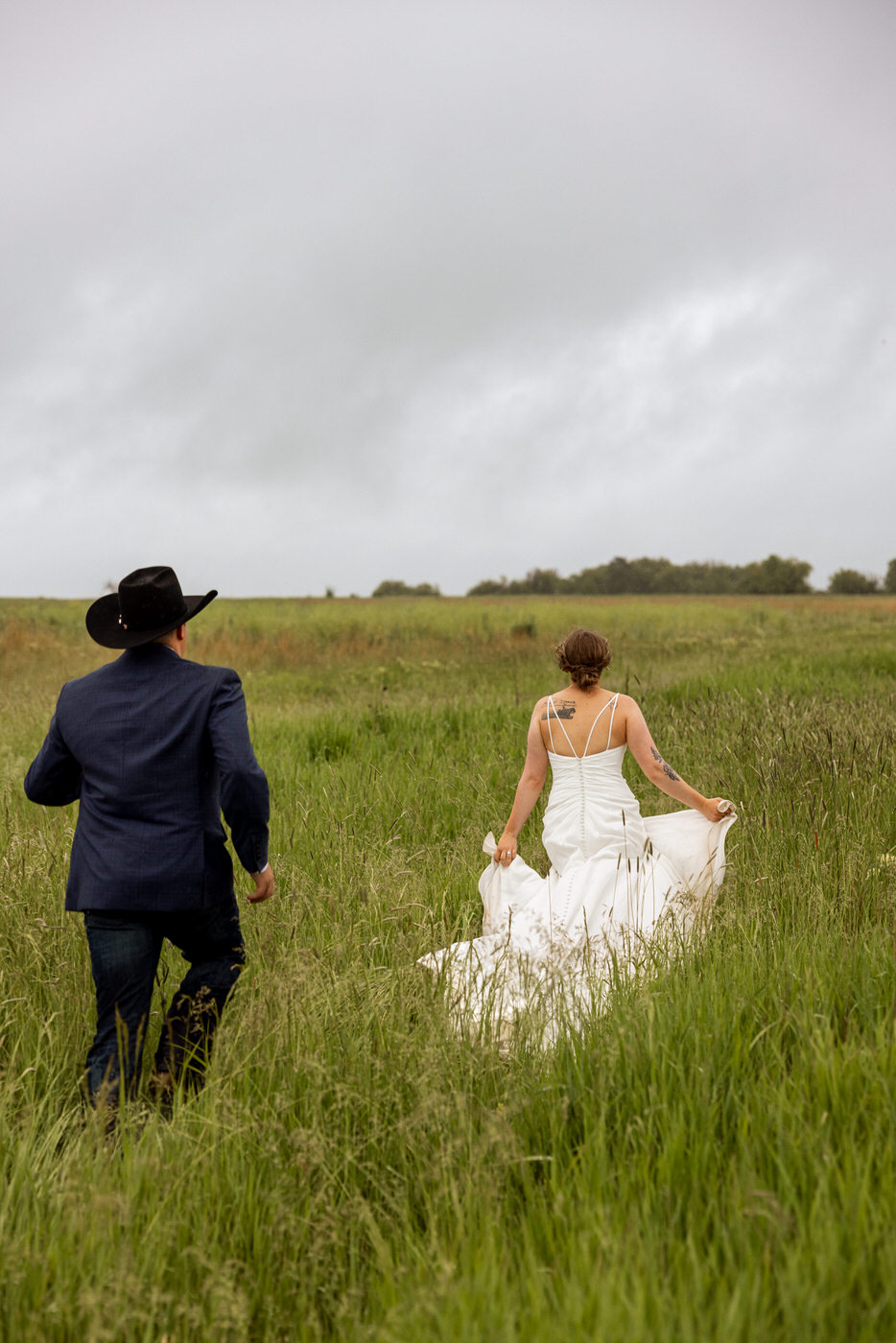 bride and groom running through a grassy field — Aislynn + Kyle — Mission Valley Wedding — Charlo Montana — Stacy Edwards Photography