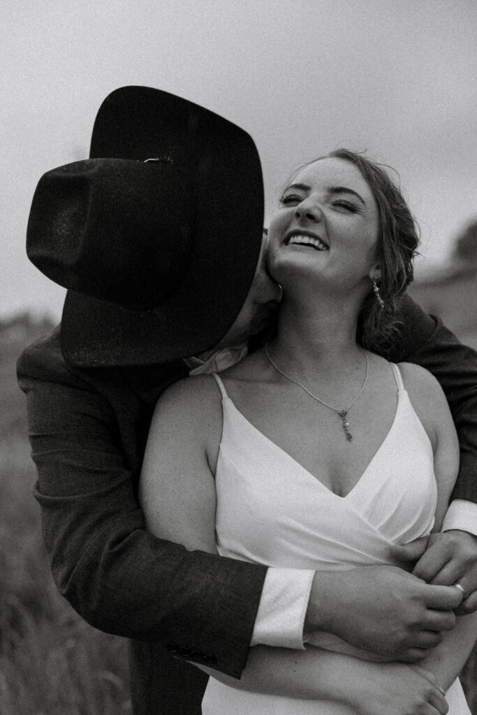 Black and white portrait of groom kissing bride on the neck — Aislynn + Kyle — Mission Valley Wedding — Charlo Montana — Stacy Edwards Photography