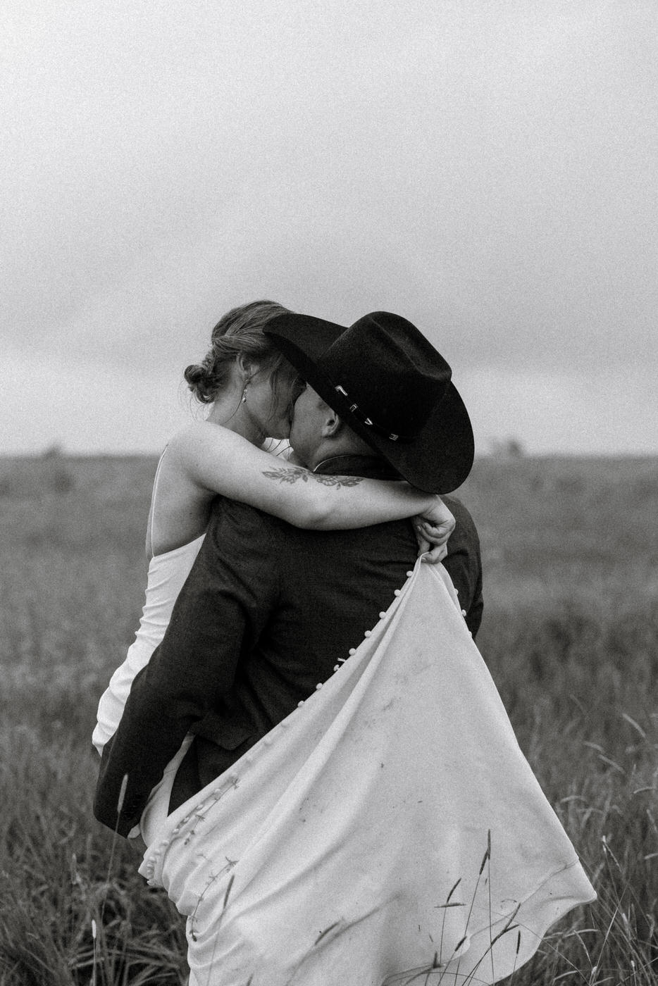 Black and white photo from behind of groom holding and kissing bride — Aislynn + Kyle — Mission Valley Wedding — Charlo Montana — Stacy Edwards Photography