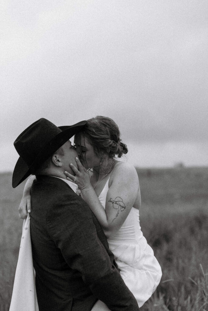 Black and white photo of groom lifting and kissing bride — Aislynn + Kyle — Mission Valley Wedding — Charlo Montana — Stacy Edwards Photography