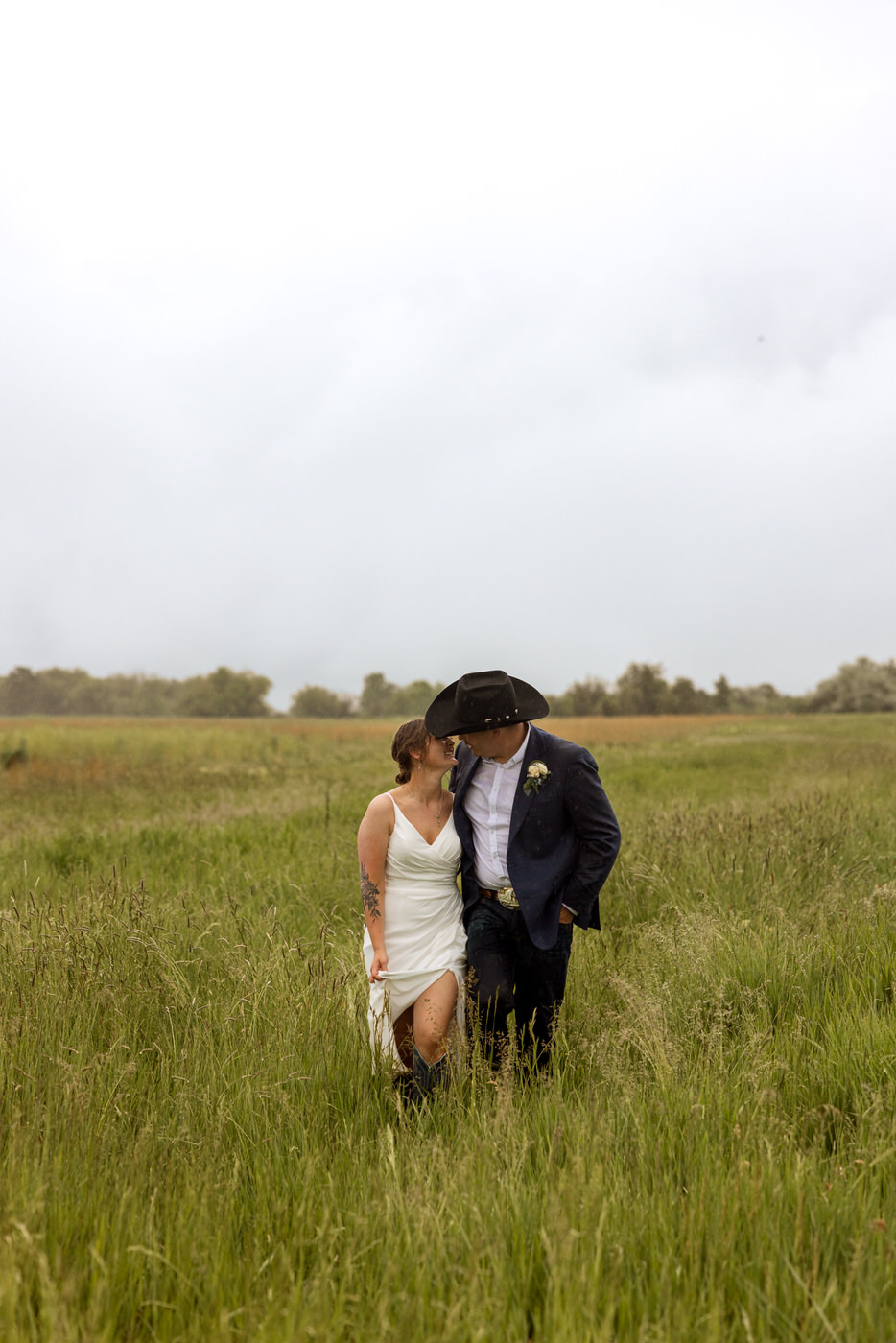Bride and groom holding each other and walking through a grassy field — Aislynn + Kyle — Mission Valley Wedding — Charlo Montana — Stacy Edwards Photography
