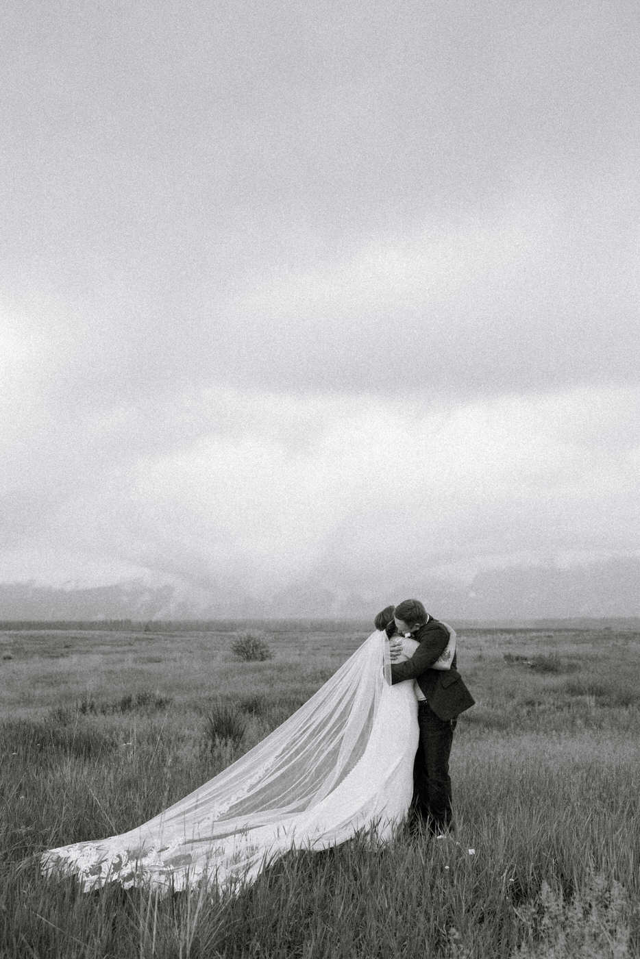 Black and White Wide Shot Photo of Bride and Groom Hugging — Aislynn + Kyle — Mission Valley Wedding — Charlo Montana — Stacy Edwards Photography