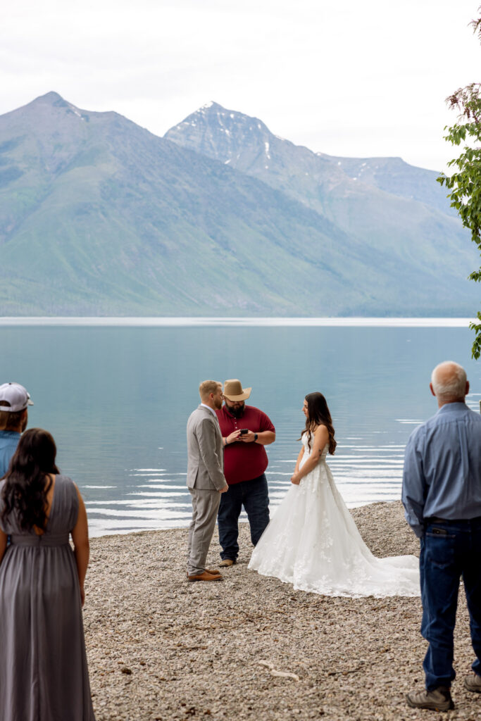 Elopement ceremony on the pebble beach at Jackson Bay with Lake McDonald and mountain peaks in the background — Glacier National Park elopement photographer Stacy Edwards Photography