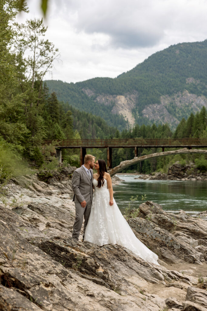 Bride and groom almost kissing on the rocks at Belton Bridge near West Glacier Montana — Glacier National Park elopement — Stacy Edwards Photography