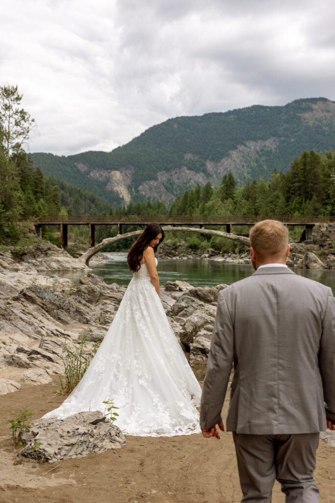 Groom walking toward bride on the rocks at Belton Bridge near West Glacier Montana — Glacier National Park elopement photographer Stacy Edwards Photography