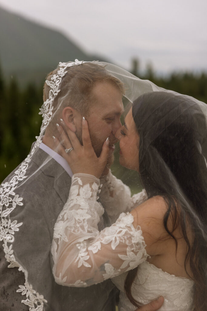 Close up of bride and groom kissing under lace veil in the rain — Belton Stage Park West Glacier Montana elopement — Stacy Edwards Photography