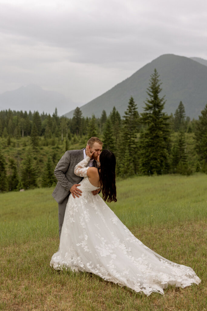 Groom dipping bride in a mountain meadow near West Glacier Montana — Glacier National Park elopement photographer Stacy Edwards Photography