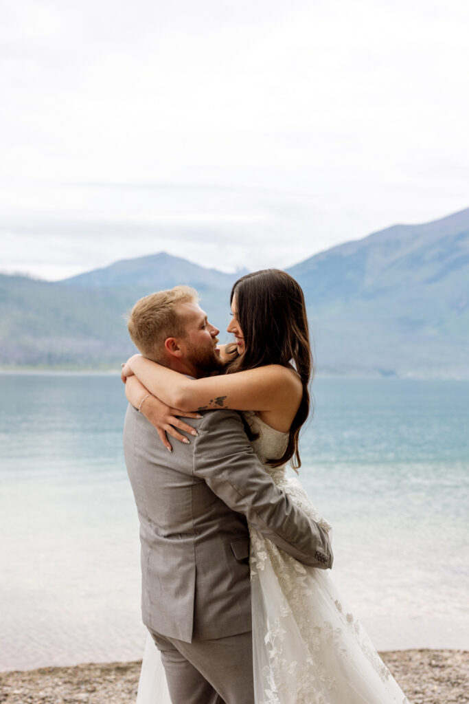Bride and groom embracing face to face on the rocky shore of Lake McDonald — Jackson Bay Glacier National Park elopement — Stacy Edwards Photography
