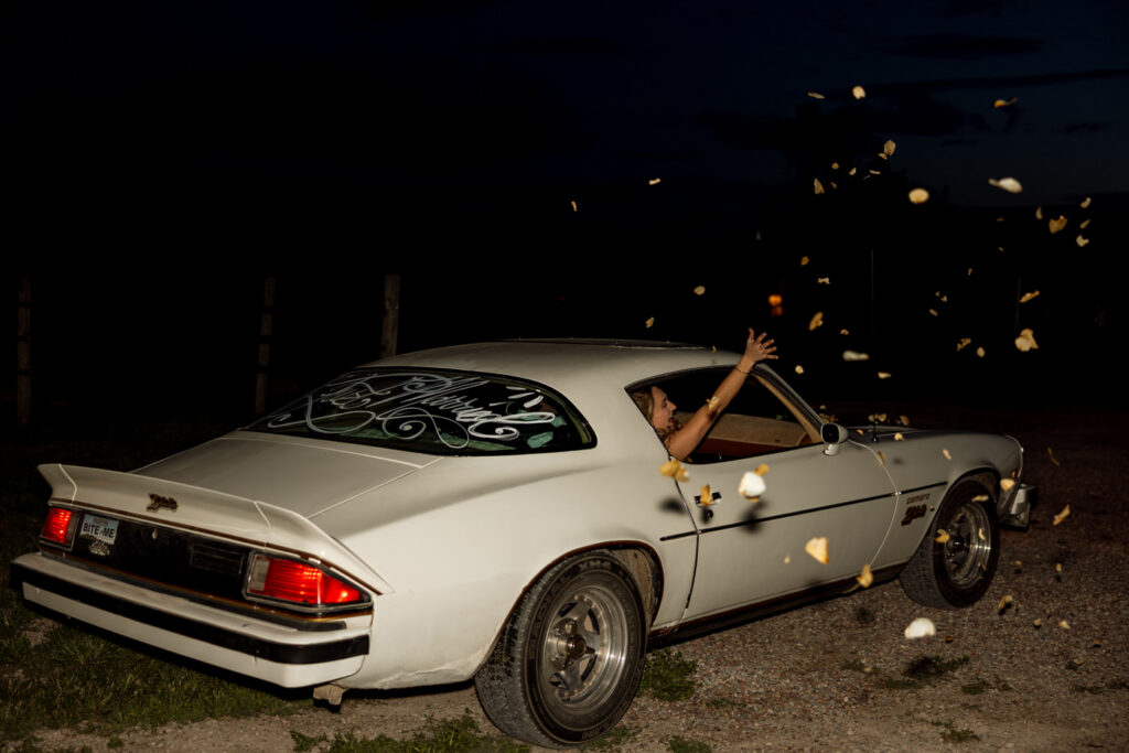 Bride sticking hand out of classic Camaro window during wedding sendoff at Ember and Altar — wedding day coverage — Montana wedding photographer Stacy Edwards Photography
