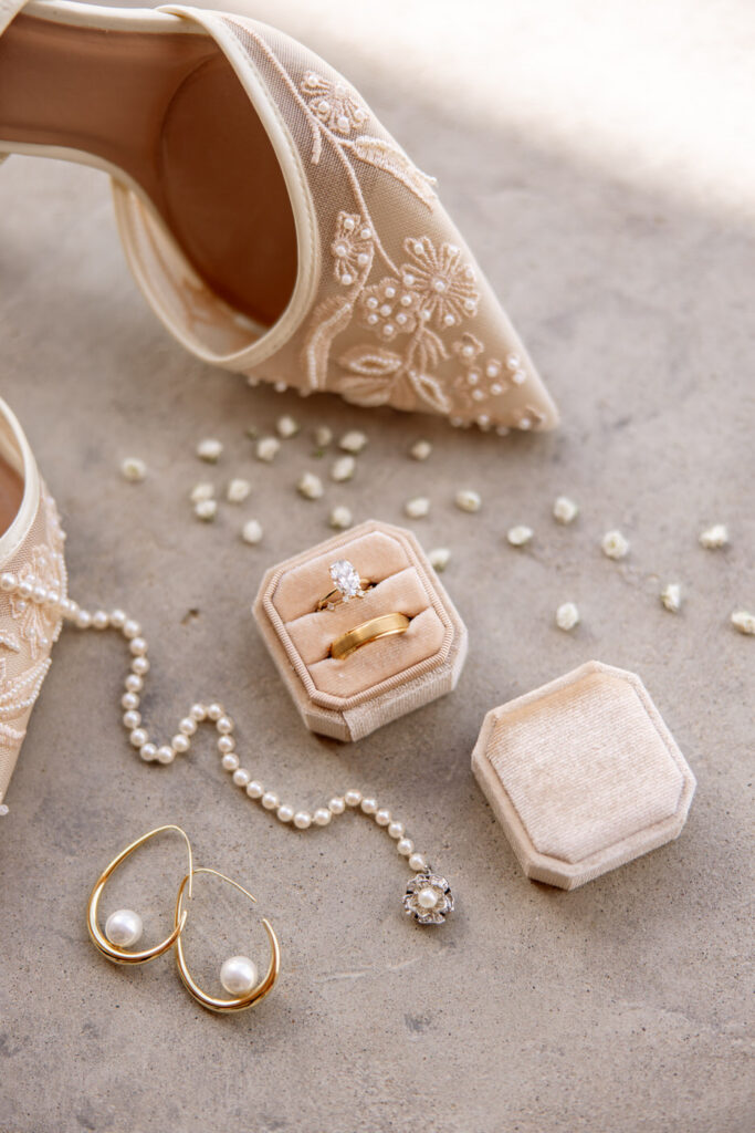 Close-up detail of bridal shoes, rings in velvet box, pearl earrings, and pearl bracelet with floral pendant — Micah + Greg — Ember & Altar Wedding — Polson Montana — Stacy Edwards Photography