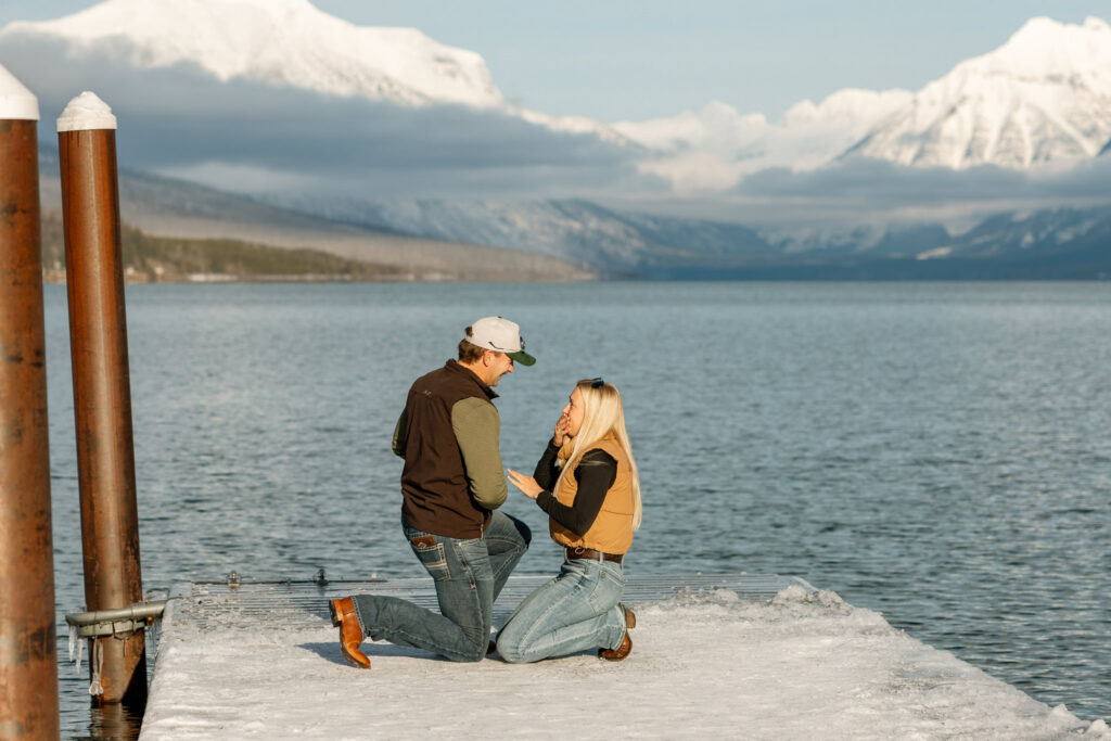 Couple sharing an emotional moment together on a snow-covered dock at Apgar Village — Lindsey and Ethan — Lake McDonald Glacier National Park Winter Proposal — Stacy Edwards Photography