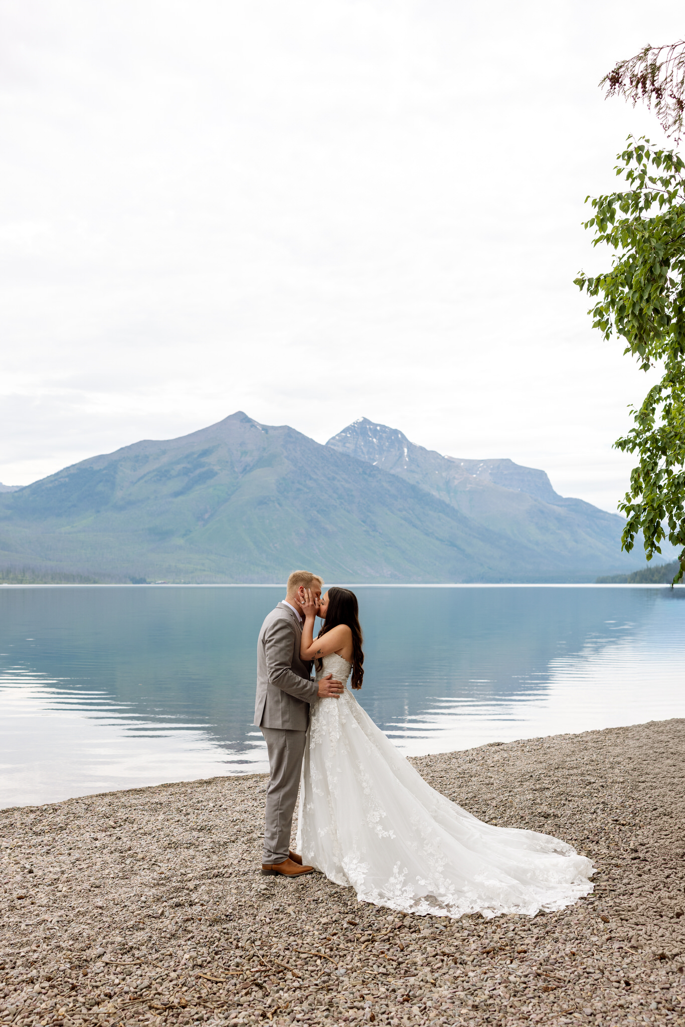 Bride and groom kissing with mountain views and Lake McDonald behind them | Glacier National Park Elopement | Stacy Edwards Photography